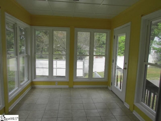 unfurnished sunroom with baseboards, tile patterned flooring, and a wealth of natural light