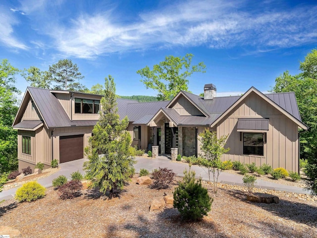 view of front facade with board and batten siding, an attached garage, driveway, and metal roof