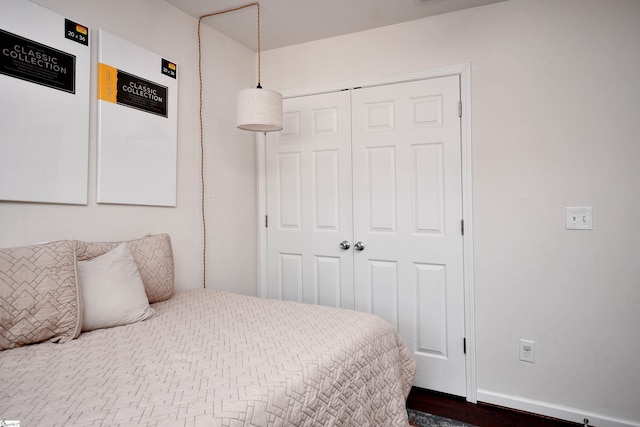 bedroom with baseboards, dark wood-style floors, and a closet