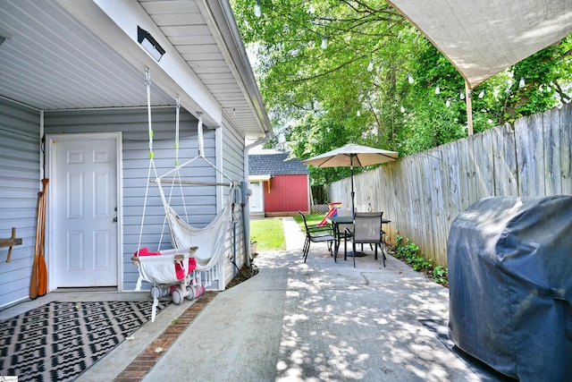 view of patio with grilling area, an outdoor structure, a fenced backyard, and outdoor dining space