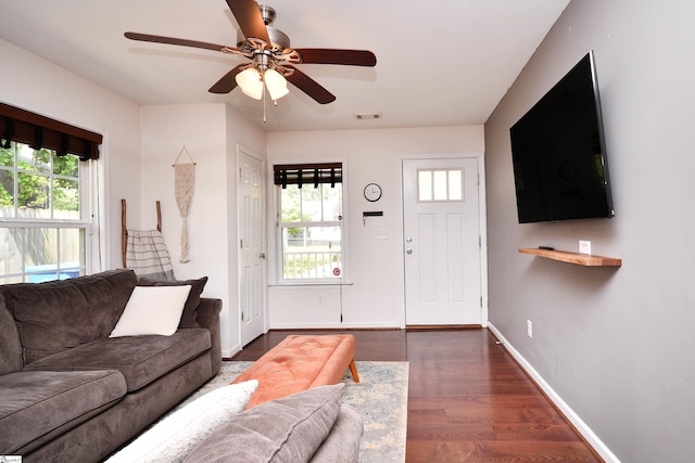 living area with visible vents, dark wood-style flooring, ceiling fan, and a healthy amount of sunlight