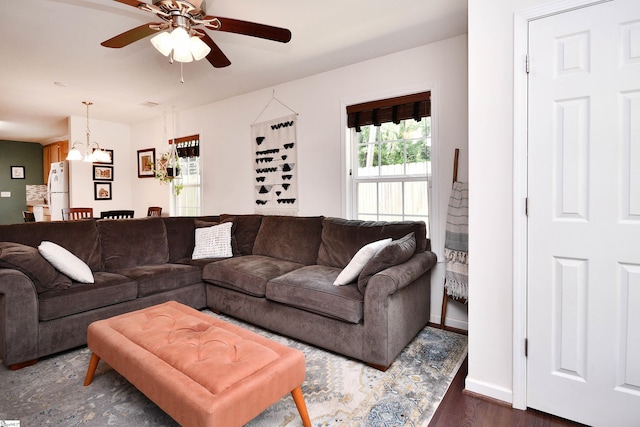 living room with baseboards, dark wood-style floors, and ceiling fan with notable chandelier