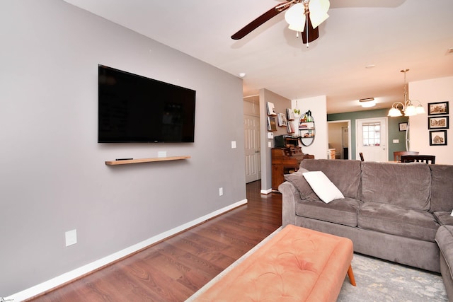 living area featuring baseboards, ceiling fan with notable chandelier, and wood finished floors