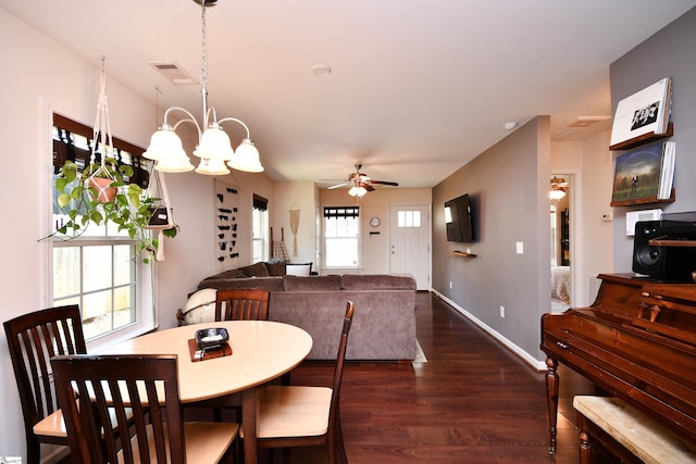dining space featuring visible vents, baseboards, dark wood finished floors, and ceiling fan with notable chandelier