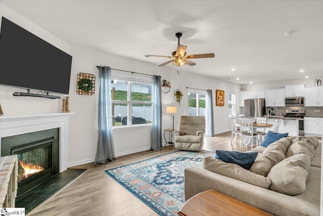 75 Oak Edge Ln, Greer, SC 29651 - living room featuring baseboards, ceiling fan, a lit fireplace, recessed lighting, and light wood finished floors