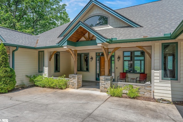 doorway to property featuring a shingled roof and covered porch