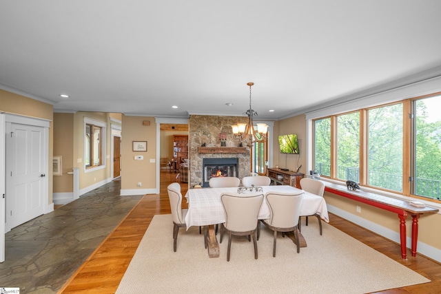 dining space with a stone fireplace, recessed lighting, baseboards, wood finished floors, and ornamental molding