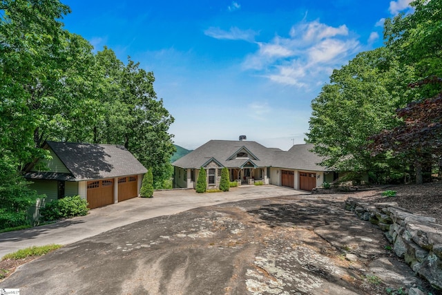 view of front of property featuring an outdoor structure, an attached garage, and concrete driveway