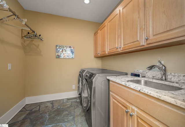 laundry area with independent washer and dryer, cabinet space, a sink, baseboards, and stone tile floors