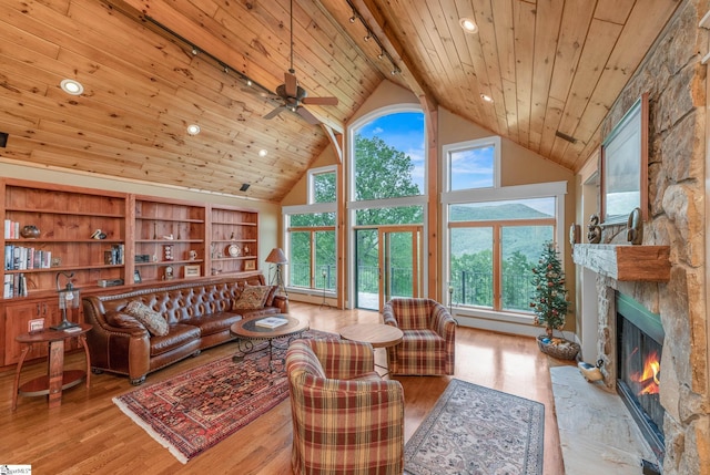 living room with ceiling fan, high vaulted ceiling, a stone fireplace, wood finished floors, and wood ceiling