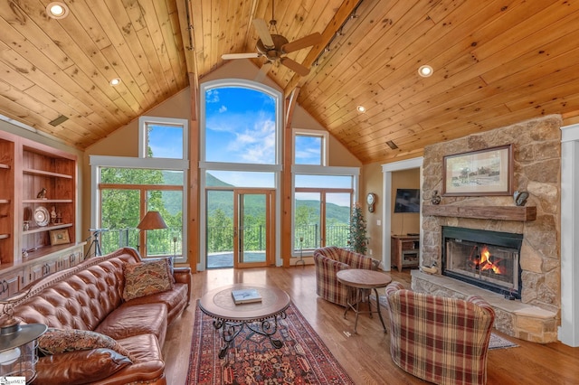 living room featuring wood finished floors, a healthy amount of sunlight, a fireplace, ceiling fan, and wood ceiling