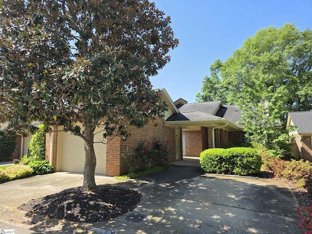 obstructed view of property featuring a garage, a shingled roof, concrete driveway, and brick siding