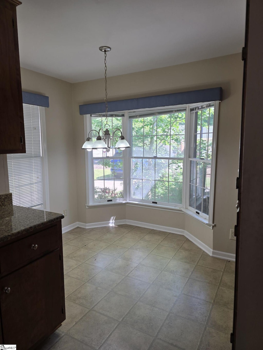 unfurnished dining area featuring baseboards and a notable chandelier