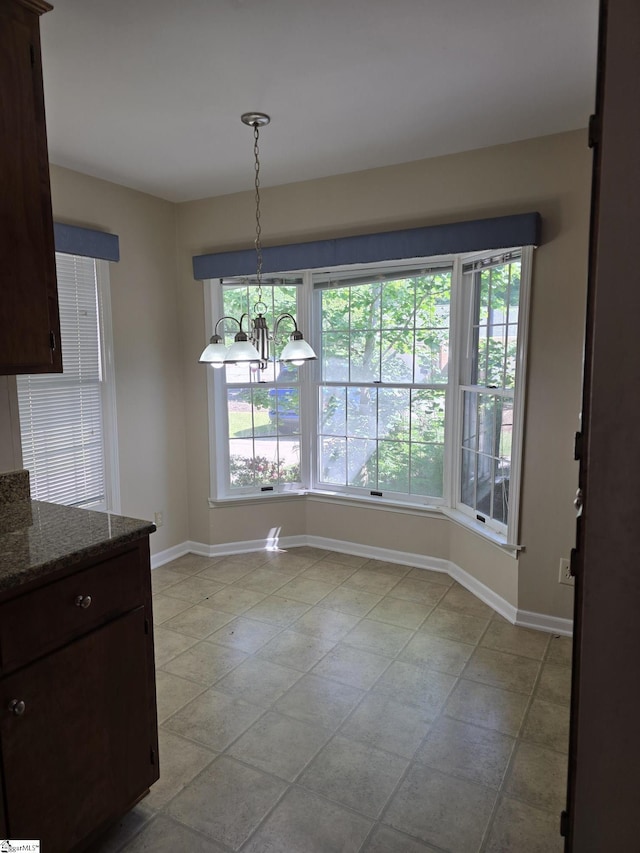 unfurnished dining area featuring baseboards and a notable chandelier
