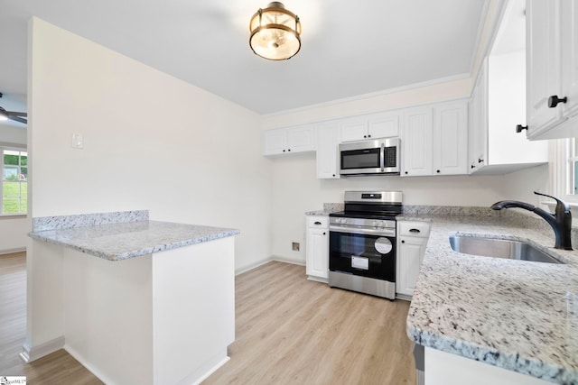 kitchen featuring light stone counters, a sink, light wood finished floors, stainless steel appliances, and a peninsula
