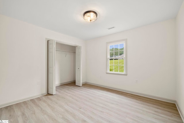 unfurnished bedroom featuring baseboards, light wood-style flooring, visible vents, and a closet