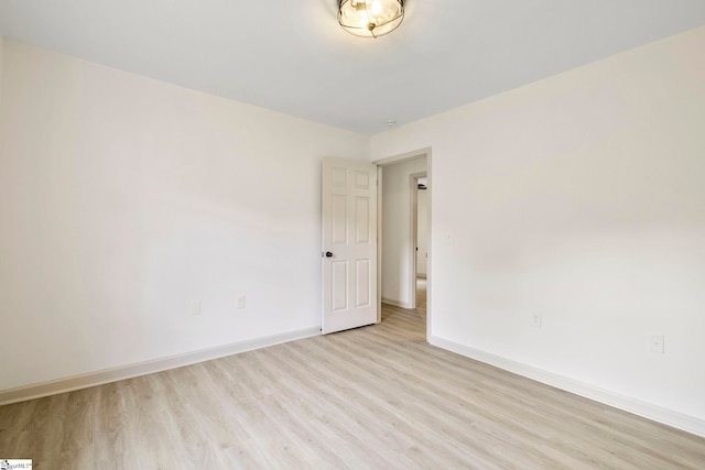 spare room featuring baseboards and light wood-style floors