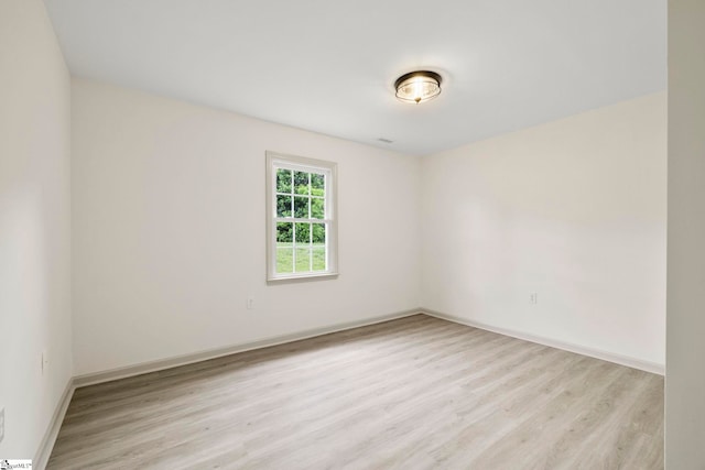 spare room featuring baseboards and light wood finished floors