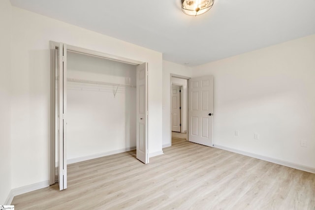 unfurnished bedroom featuring baseboards, a closet, and light wood finished floors