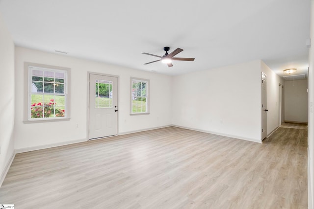 unfurnished living room with ceiling fan, light wood-style flooring, attic access, baseboards, and visible vents