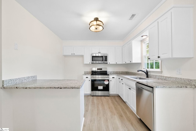 kitchen featuring visible vents, light wood-type flooring, light stone counters, a sink, and stainless steel appliances