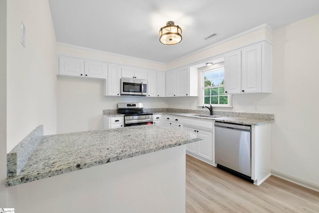 kitchen featuring appliances with stainless steel finishes, a sink, light wood finished floors, white cabinetry, and visible vents