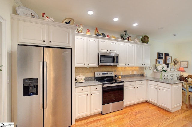 132 Hartsfield Dr, Easley, SC 29642 - kitchen featuring appliances with stainless steel finishes, tasteful backsplash, a peninsula, light wood finished floors, and white cabinetry