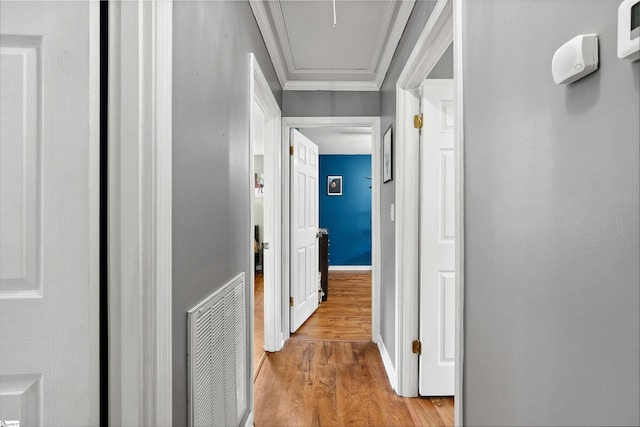 corridor with crown molding, light wood finished floors, attic access, baseboards, and visible vents