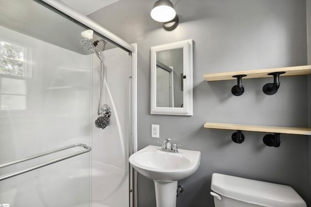 bathroom featuring a sink, a stall shower, and toilet
