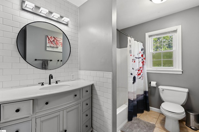 bathroom with tile walls, shower / bath combo, tile patterned floors, vanity, and toilet