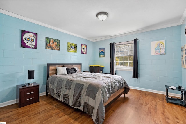bedroom with baseboards, ornamental molding, and wood finished floors