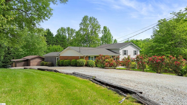 view of front facade with brick siding, driveway, and an outdoor structure