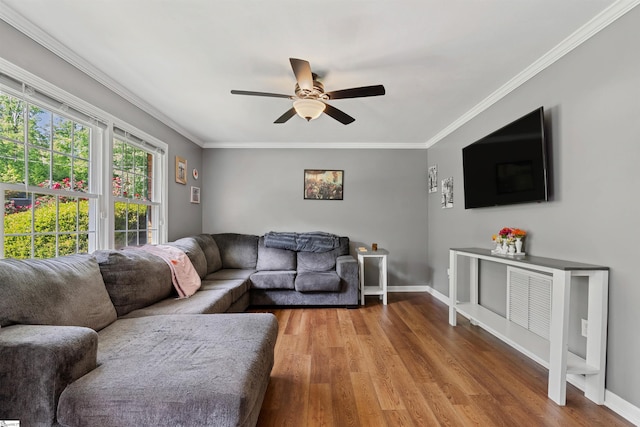 living area featuring baseboards, ornamental molding, ceiling fan, and wood finished floors