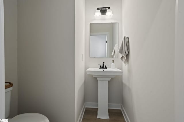 bathroom featuring a sink, baseboards, toilet, and wood finished floors