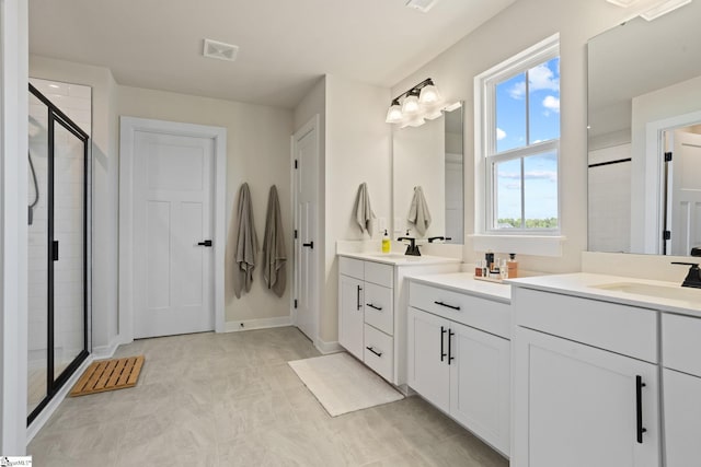 bathroom with vanity, baseboards, a shower stall, and visible vents