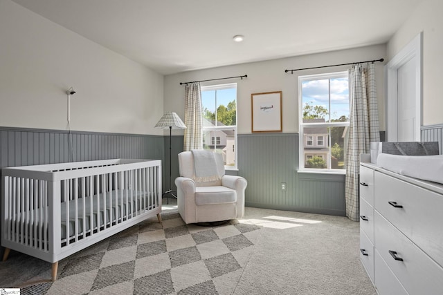 carpeted bedroom featuring a nursery area, wainscoting, and recessed lighting