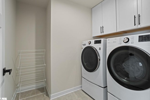 washroom featuring baseboards, cabinet space, and washer and dryer