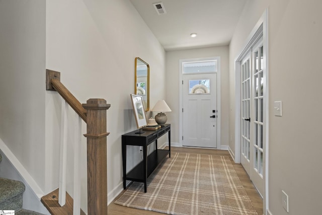 foyer entrance featuring stairs, baseboards, visible vents, and wood finished floors