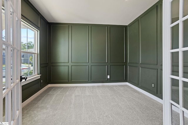 spare room with light carpet, french doors, and a decorative wall