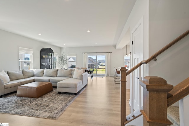 living area with recessed lighting, stairway, a wealth of natural light, and light wood-style flooring