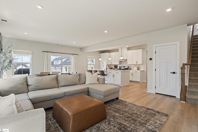 living area with stairs, recessed lighting, and light wood-type flooring