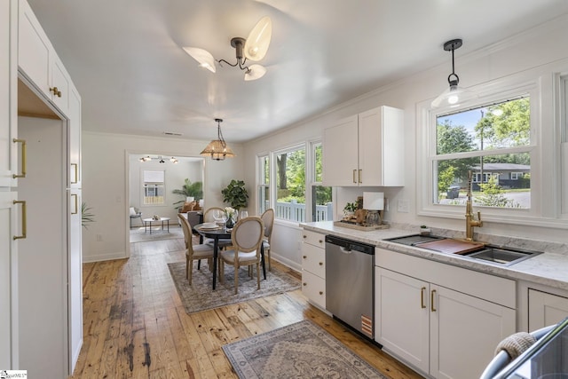 kitchen with a sink, white cabinetry, light wood-type flooring, stainless steel dishwasher, and ornamental molding