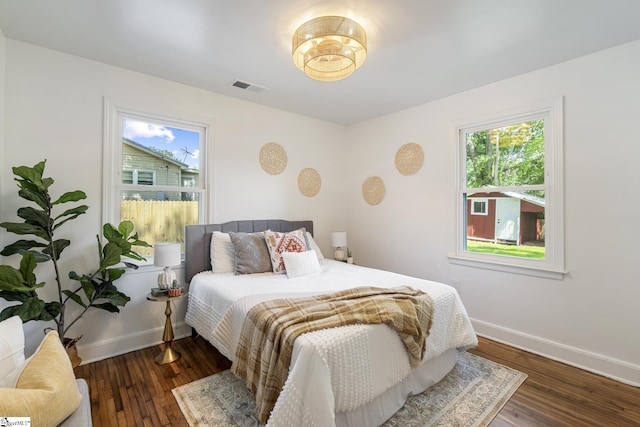 bedroom with baseboards, wood finished floors, and visible vents