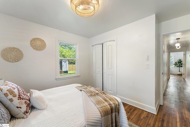 bedroom featuring wood-type flooring, baseboards, and a closet