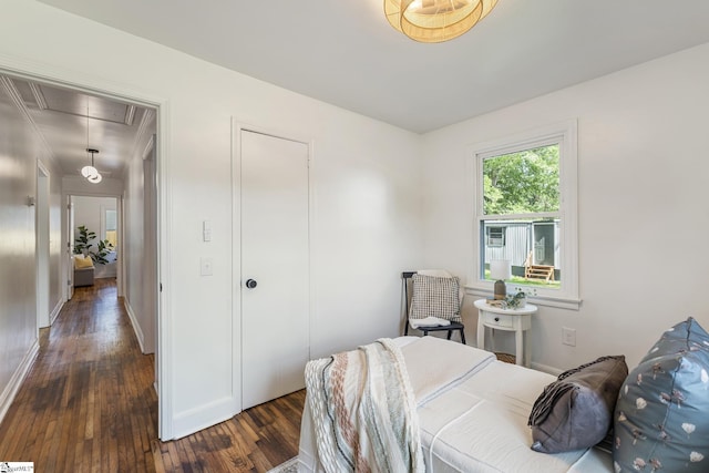 bedroom with baseboards, attic access, and dark wood-type flooring