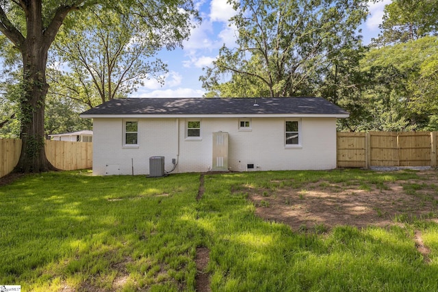 rear view of property featuring a fenced backyard, a lawn, central AC, and brick siding