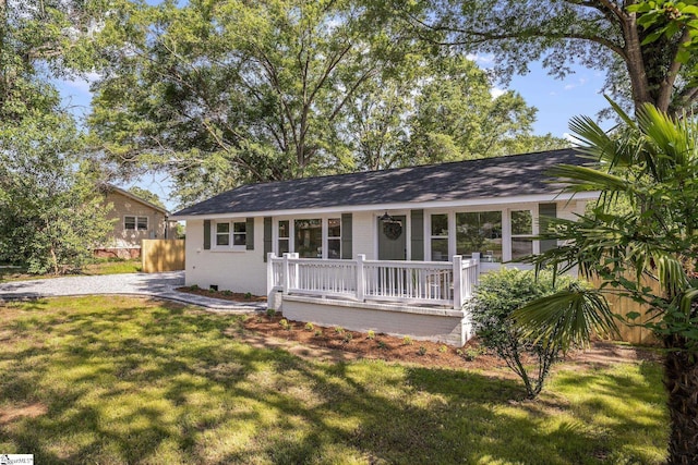 ranch-style house with covered porch, fence, and a front lawn