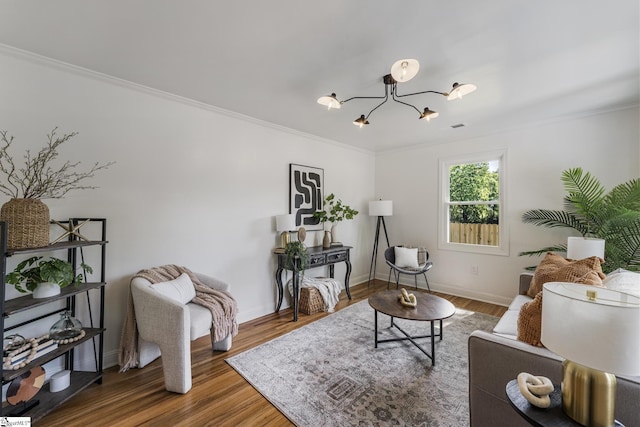 living area with crown molding, baseboards, wood finished floors, and a chandelier