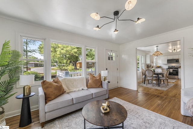 living area featuring an inviting chandelier, ornamental molding, and a wealth of natural light