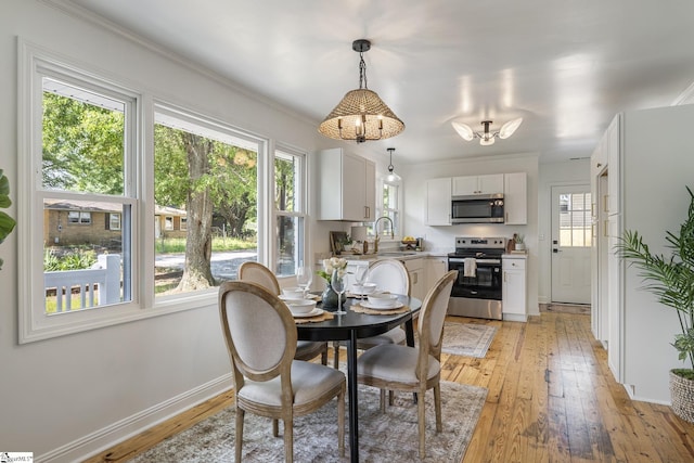 dining space featuring light wood-style floors, baseboards, and crown molding